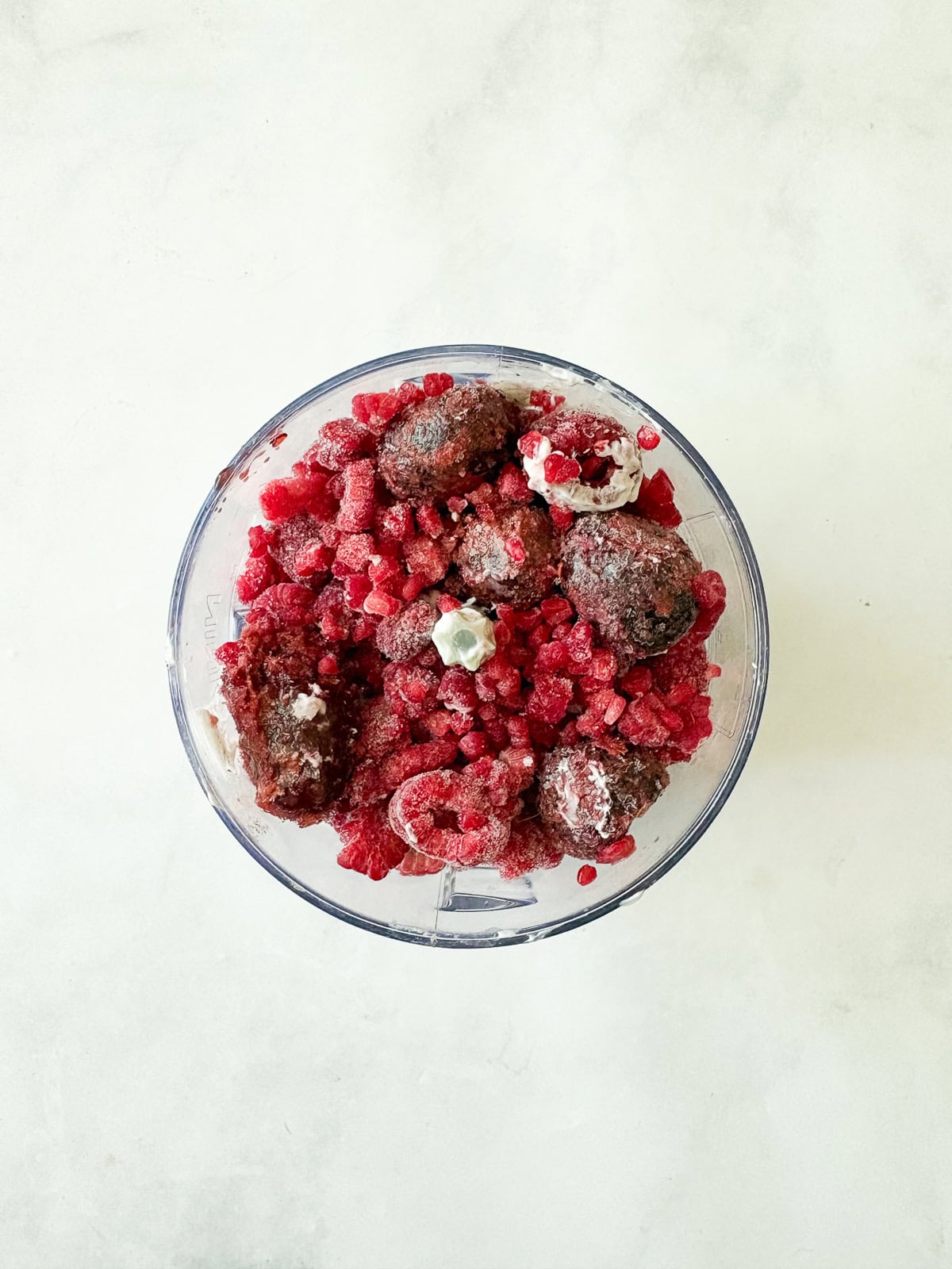 Just two ingredients - fruit and yogurt - plus a food processor are needed to make this refreshing and easy homemade Greek frozen yogurt. Frozen fruit is added to yogurt in a food processor.
