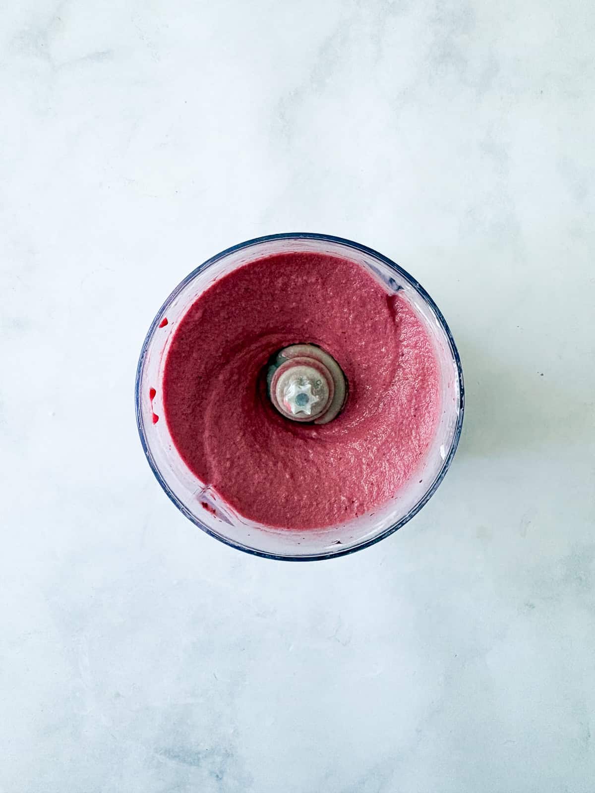 Just two ingredients - fruit and yogurt - plus a food processor are needed to make this refreshing and easy homemade Greek frozen yogurt. A food processor with the final result of Greek frozen yogurt.
