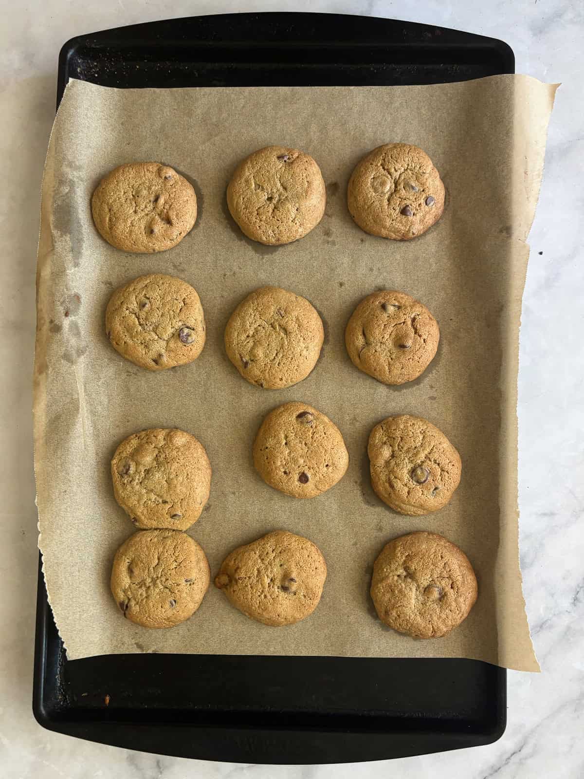 One of my favorite types of cookies, these maple chocolate chip cookies are sweetened with a combination of maple syrup and brown sugar. A baking tray with baked maple syrup chocolate chip cookies.