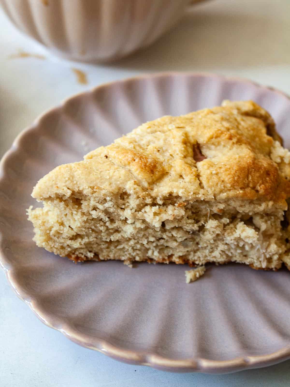 Whole-grain oat flour rhubarb scones are naturally gluten-free, warmed with a bit of orange zest and studded with jammy pockets of rhubarb. An oat flour rhubarb scone on a purple plate.