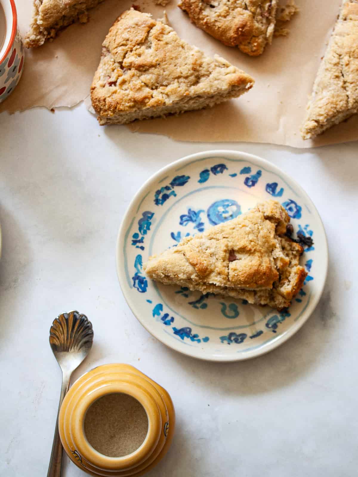 Strawberry rhubarb scones next to a sugar bowl and a spoon.