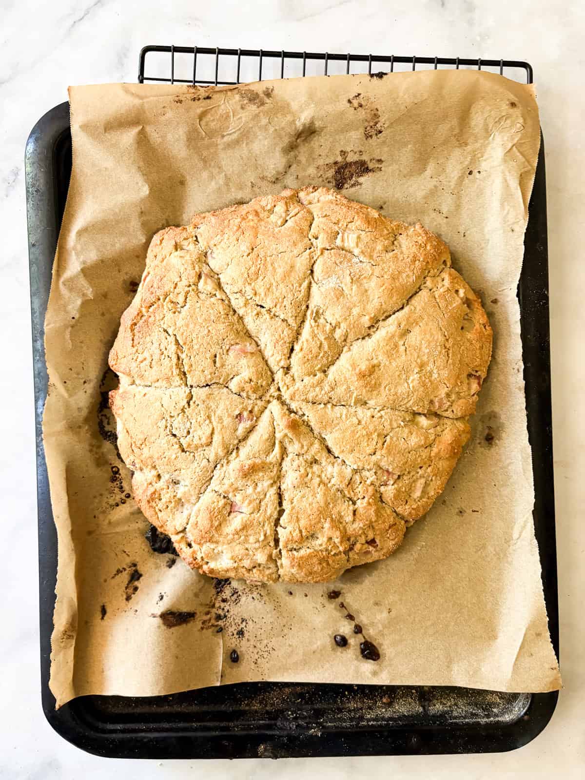 Tender and flaky whole grain strawberry rhubarb scones are a perfect summer morning treat. Make these with whole wheat or gf oat flour. Strawberry rhubarb scones cool on a baking tray.
