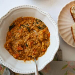 A spoon rests in a bowl of red lentil stew.