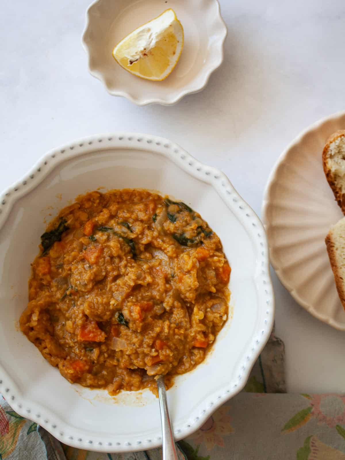 A spoon rests in a bowl of red lentil stew.