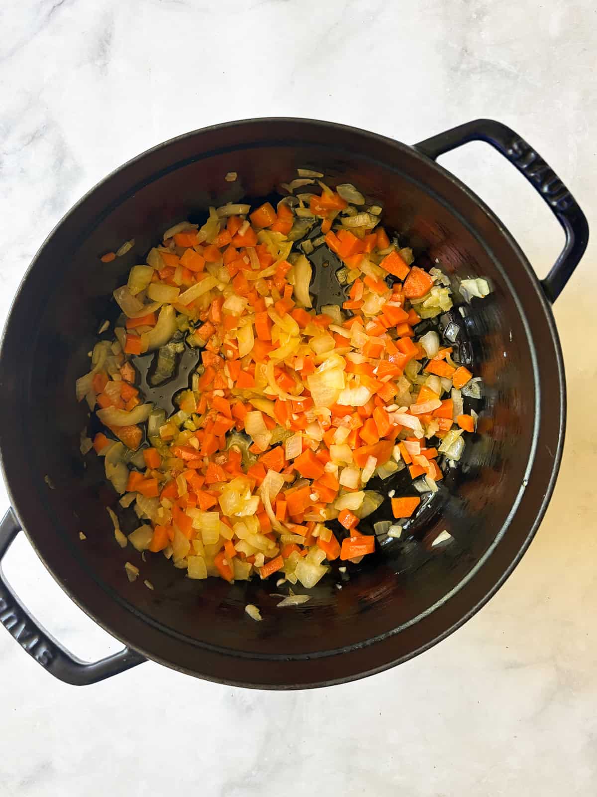 A hearty vegetarian red lentil stew that's packed with vegetables to make a satisfying dinner. Easy to adapt and make-ahead friendly. Garlic, carrots and onion cook in a dutch oven.