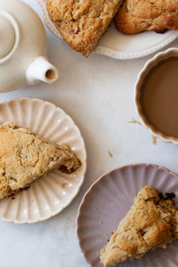 A tea pot and a cup of tea next to whole wheat rhubarb scones.