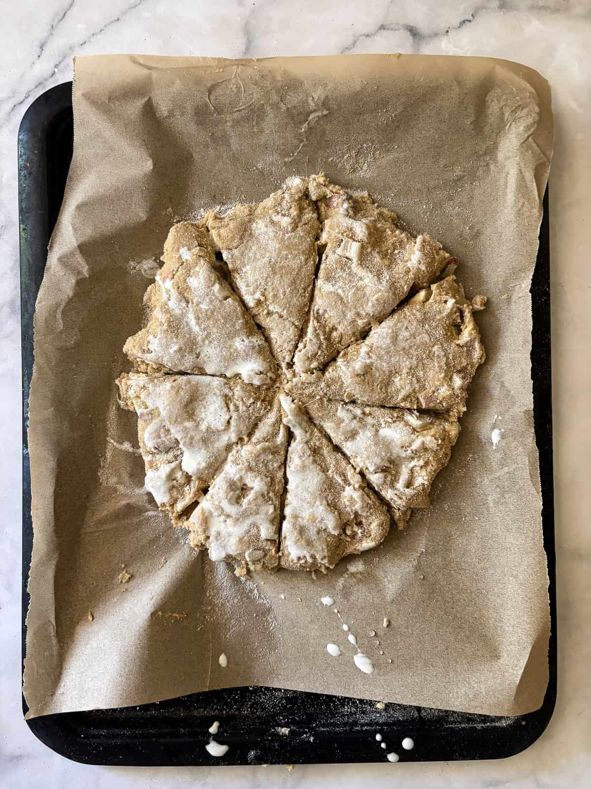Tender, flaky rhubarb scones made with whole wheat flour and lots of tart spring rhubarb and a hint of orange zest. Cutting the dough into wedges.
