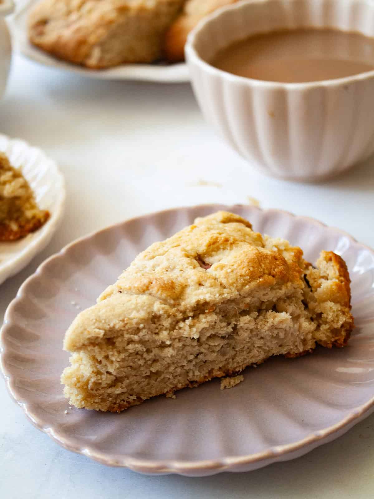 Tender, flaky rhubarb scones made with whole wheat flour and lots of tart spring rhubarb and a hint of orange zest. A side view of a whole wheat rhubarb scone on a plate.