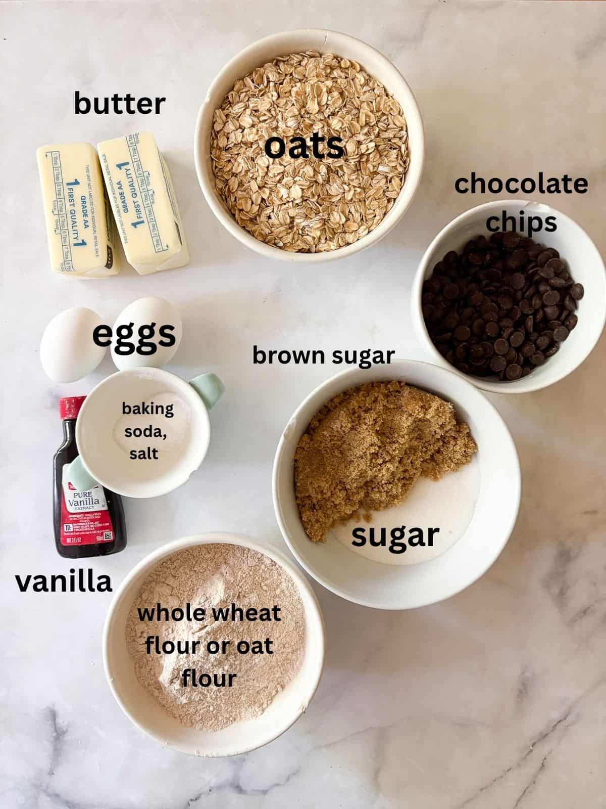 Soft and chewy-crisp chocolate chip oatmeal cookies are packed with the good stuff - butter, rolled oats, whole grain flour, and chocolate! Ingredients for chocolate chip oatmeal cookies are text-labeled.
