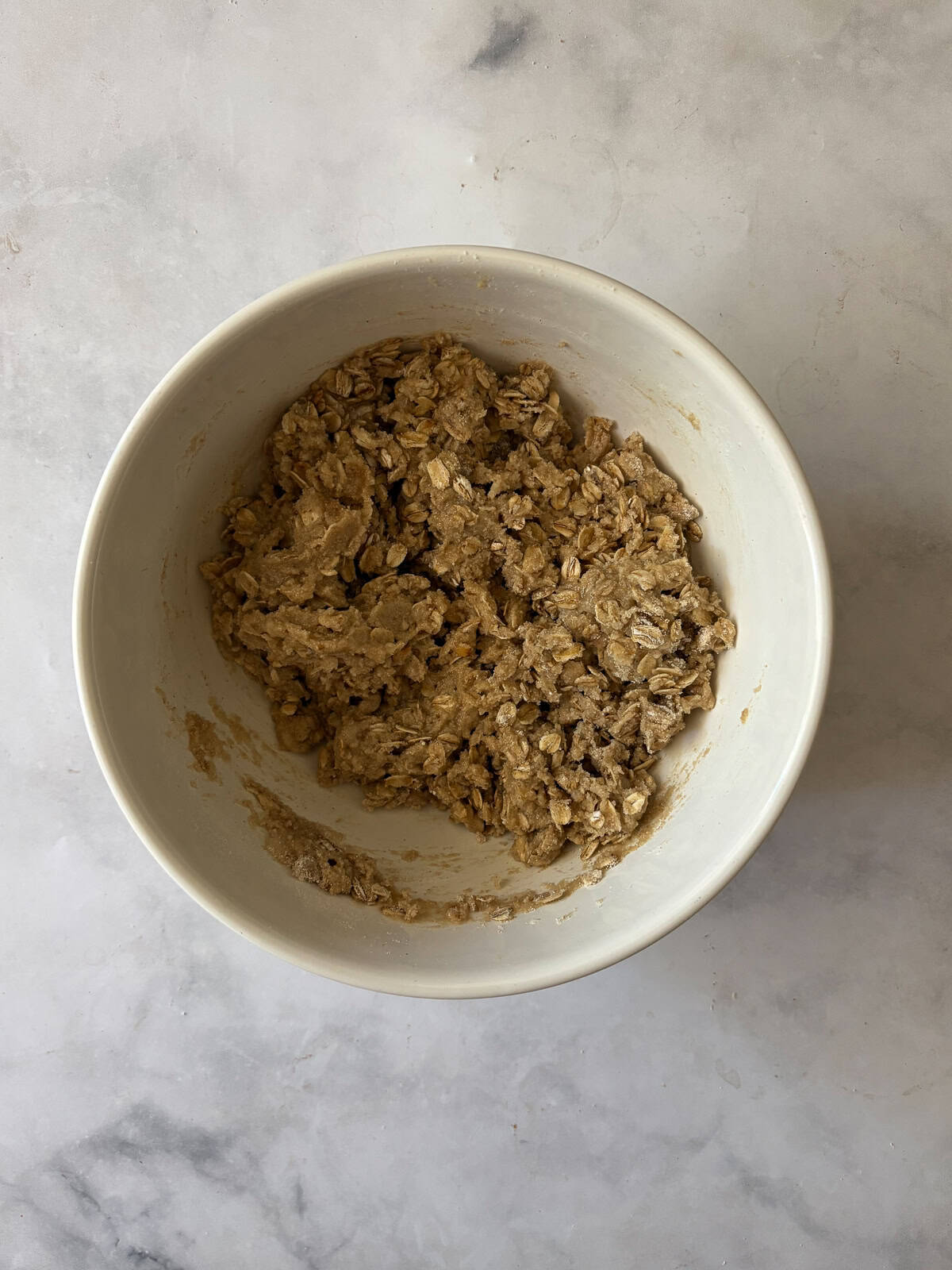 A jammy apple rhubarb crisp pairs seasonal rhubarb with sweet apples. Make the buttery oat topping gluten-free or use whole wheat flour. The oat topping is mixed together for apple rhubarb crisp in a bowl.