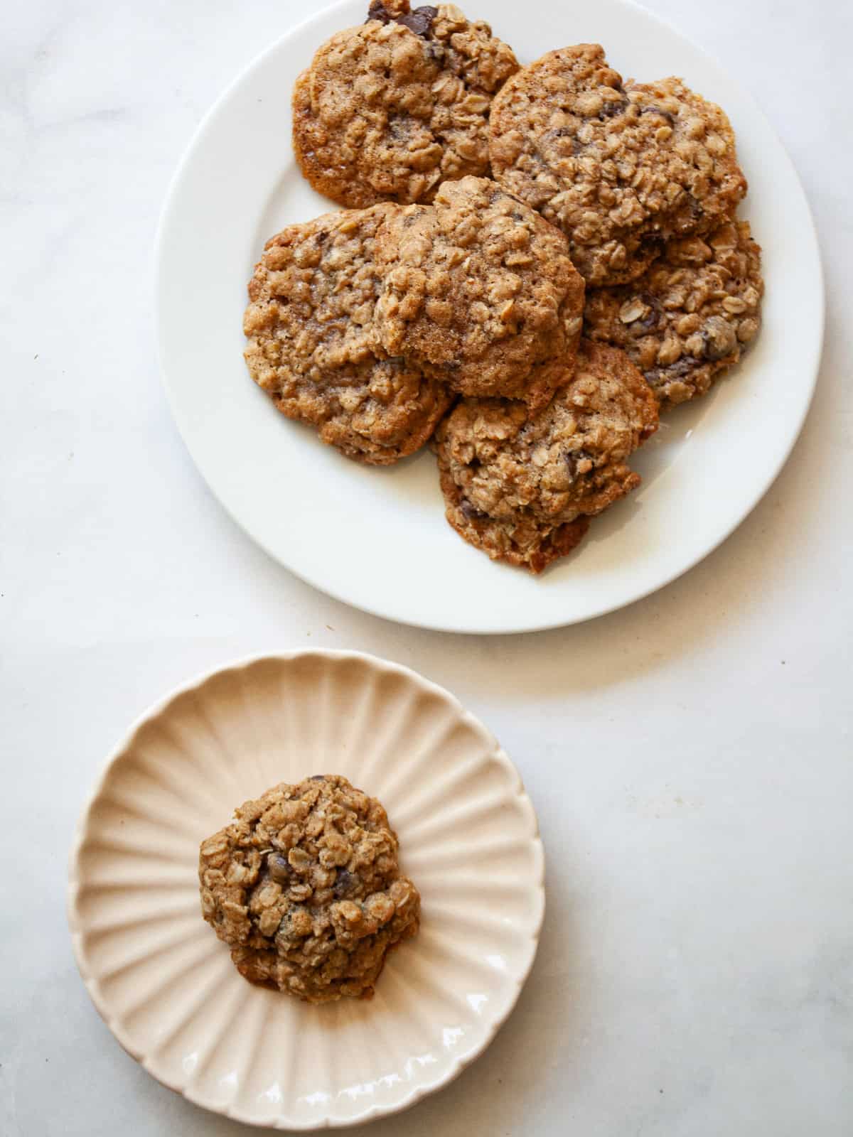 Soft and chewy-crisp chocolate chip oatmeal cookies are packed with the good stuff - butter, rolled oats, whole grain flour, and chocolate! Chocolate chip oatmeal cookies on a plate and one cookie on a plate.