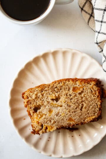 A slice of gluten free peach quick bread on a plate.
