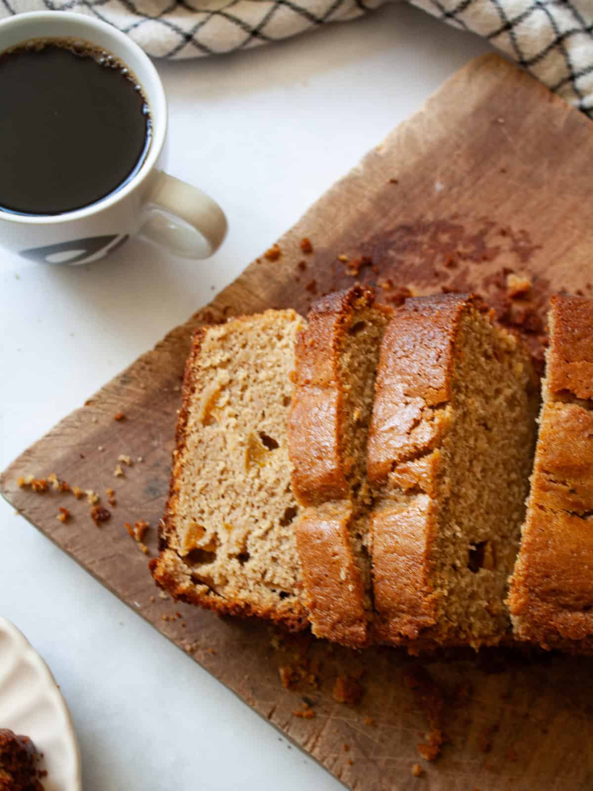 A sliced loaf of gluten free peach bread on a cutting board.