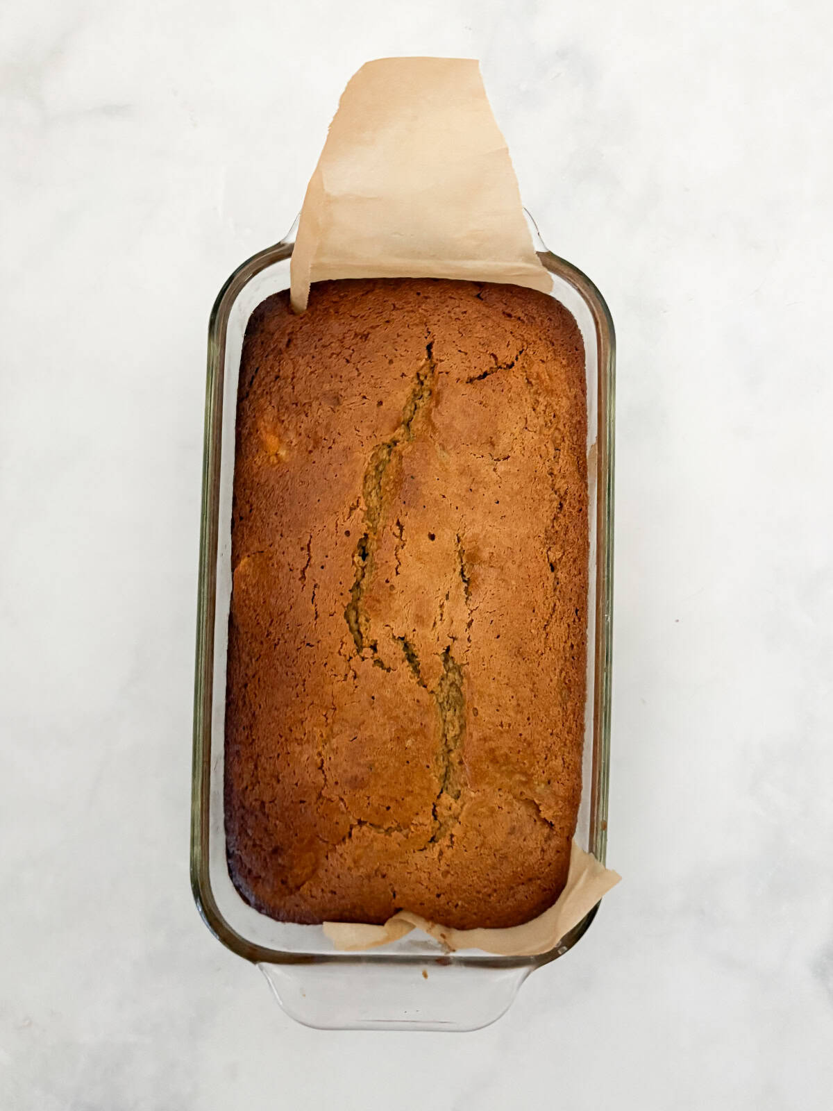 Juicy fresh peaches infuse this gluten-free peach quick bread with sweet summer flavor! Made with whole-grain oat flour and fresh fruit. A loaf of gluten free peach quick bread cools in a loaf pan.
