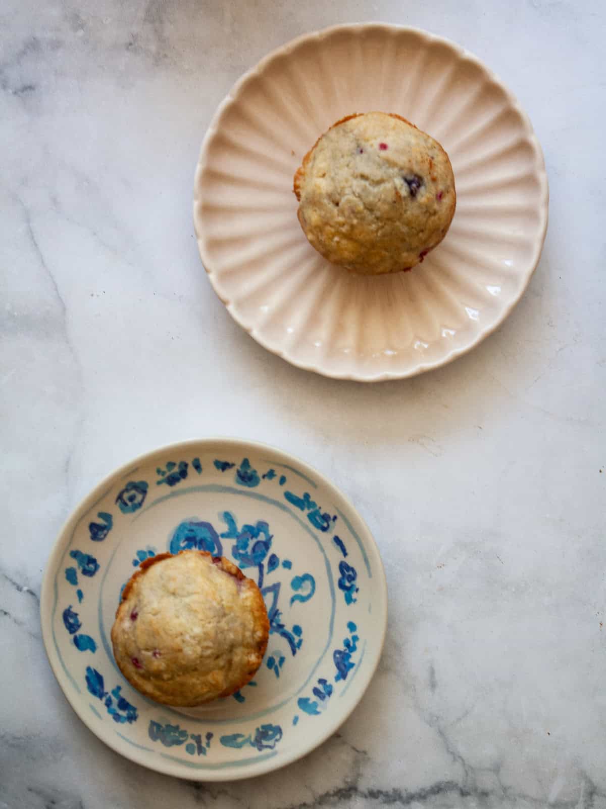 These delicious gluten-free raspberry muffins are made in one bowl and are packed with wholesome ingredients and fruit! Two gluten free raspberry muffins on plates.