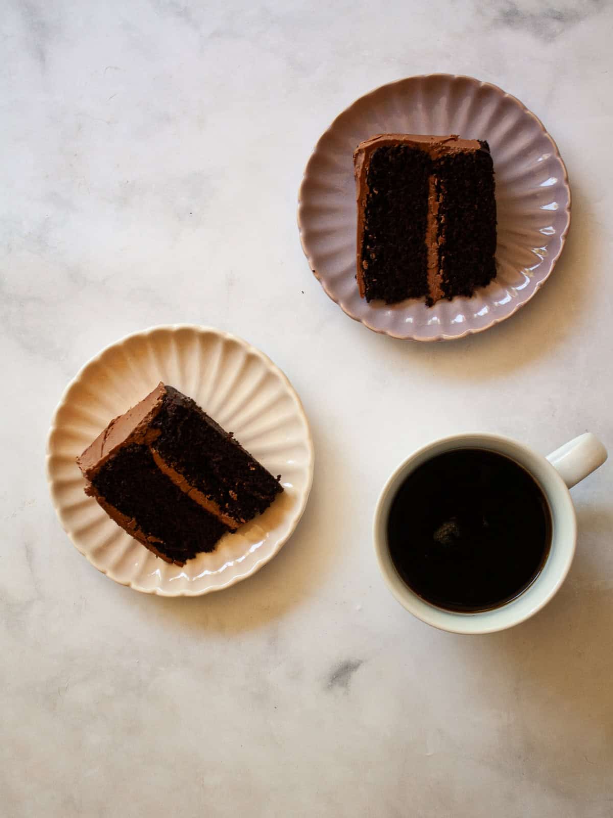 This tender, naturally higher-protein chocolate cake delivers 8 grams of protein per slice from whole foods ingredients. NO protein powder! Two slices of higher protein chocolate cake on plates with a cup of coffee.