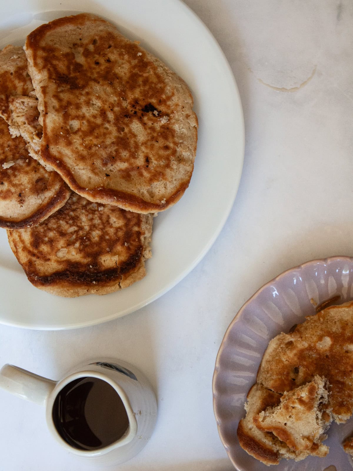 These strawberry pancakes feature fresh, juicy strawberries, whole grain flour, and a light and fluffy crumb. Gluten-free if needed. A plate of strawberry pancakes and a small pitcher of maple syrup.