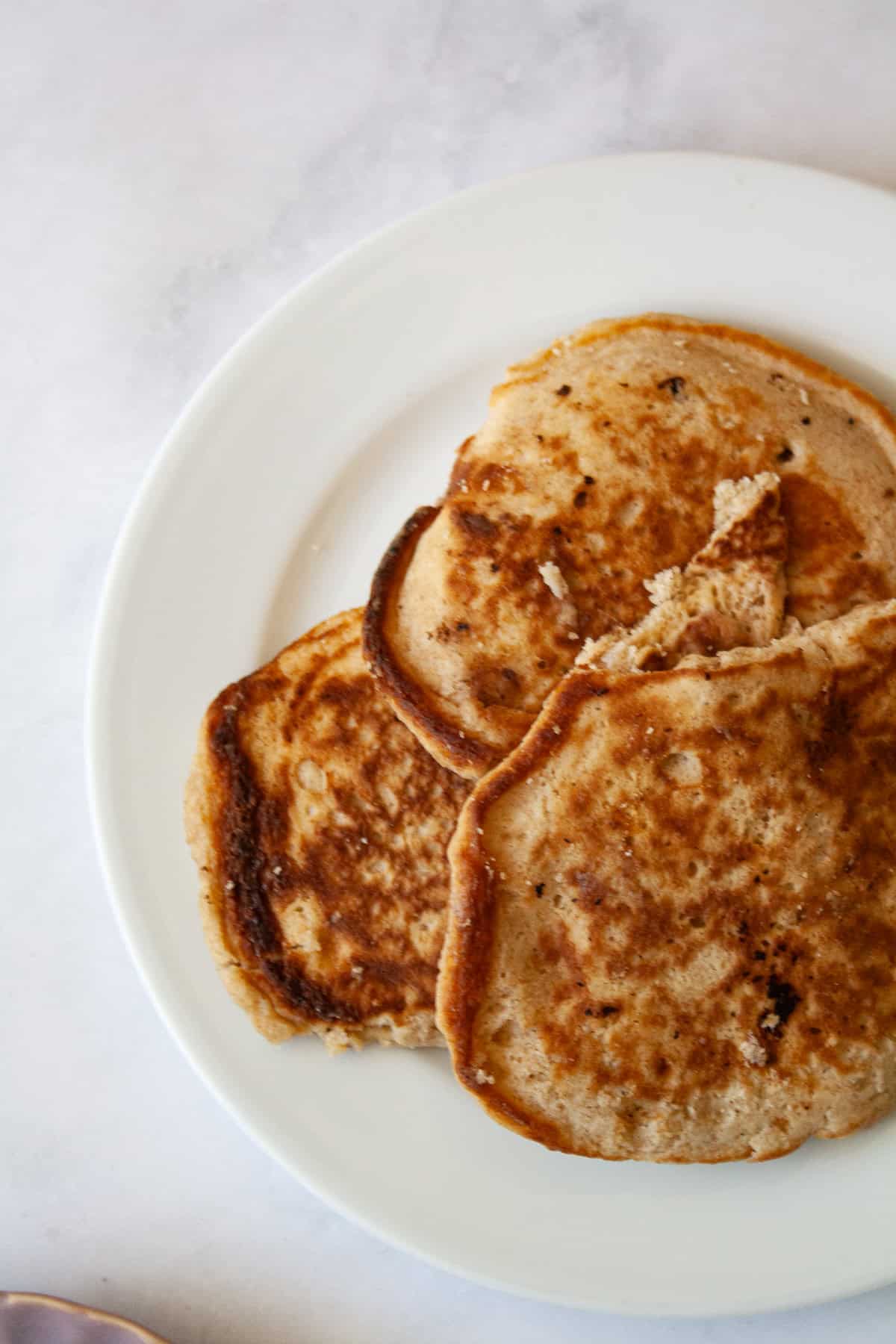 These strawberry pancakes feature fresh, juicy strawberries, whole grain flour, and a light and fluffy crumb. Gluten-free if needed. Strawberry pancakes arranged on a white plate.