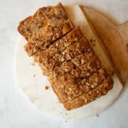 A sliced loaf of whole grain peach bread on a cutting board.