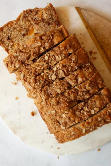 A sliced loaf of whole grain peach bread on a cutting board.