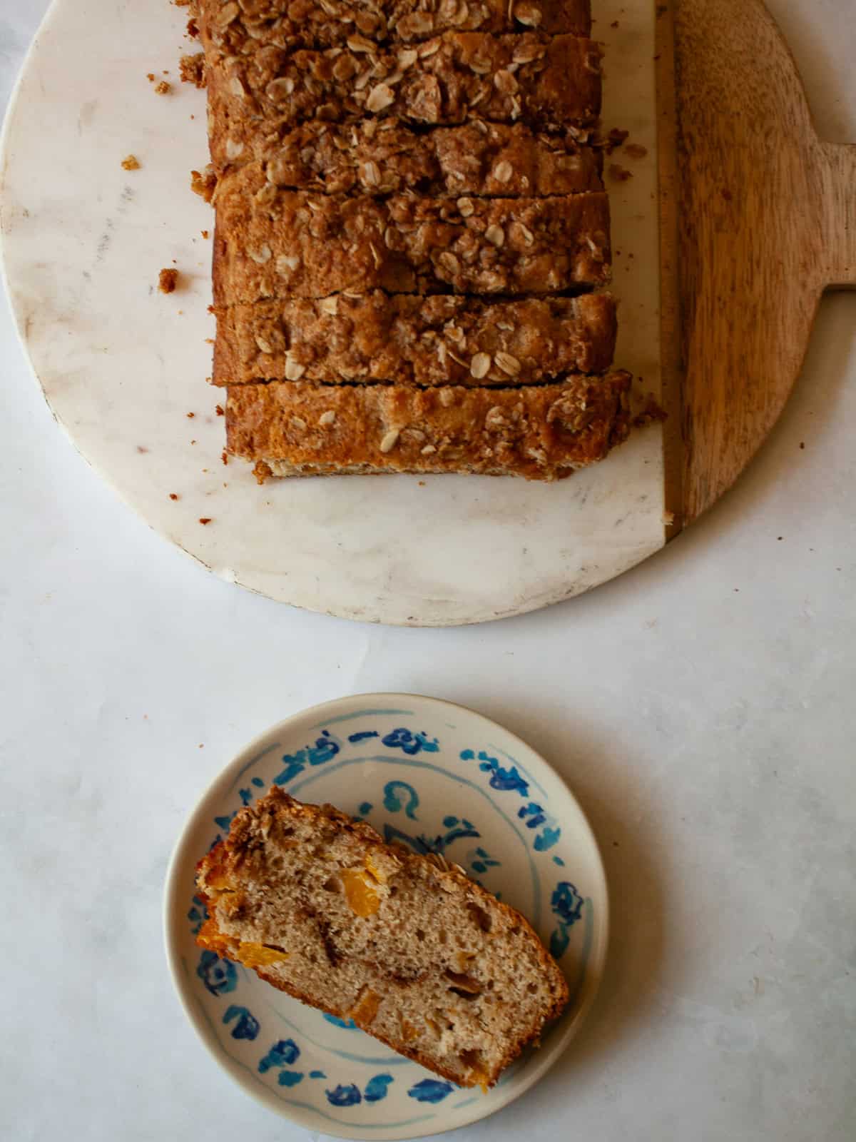 A crisp and cozy oat topping makes this whole grain peach bread shine! Featuring juicy bites of peaches and a brown sugar-cinnamon swirl. A slice of whole grain peach bread and the loaf next to it.