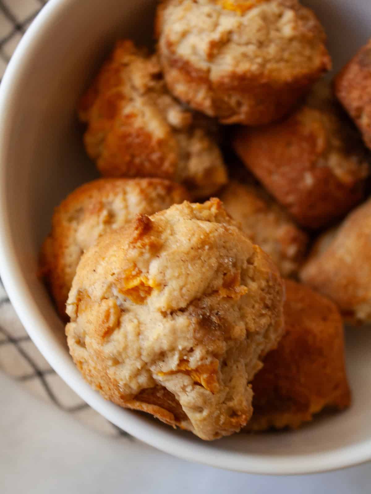 Yogurt, whole grains, and juicy peaches are swirled together with brown sugar in these tender and good-for-you gluten free peach muffins. A close up shot of gluten free peach muffins.