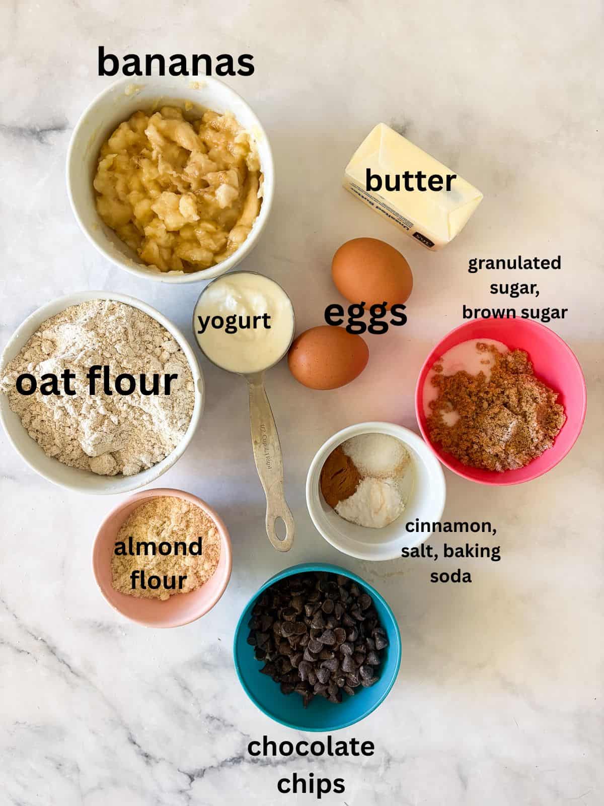An easy gluten free batter packed with whole grains and yogurt makes for the best loaf of gluten free chocolate chip banana bread. Ingredients for gluten free chocolate chip banana bread are text-labeled.