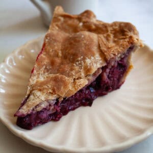 A slice of homemade blackberry pie on a plate.