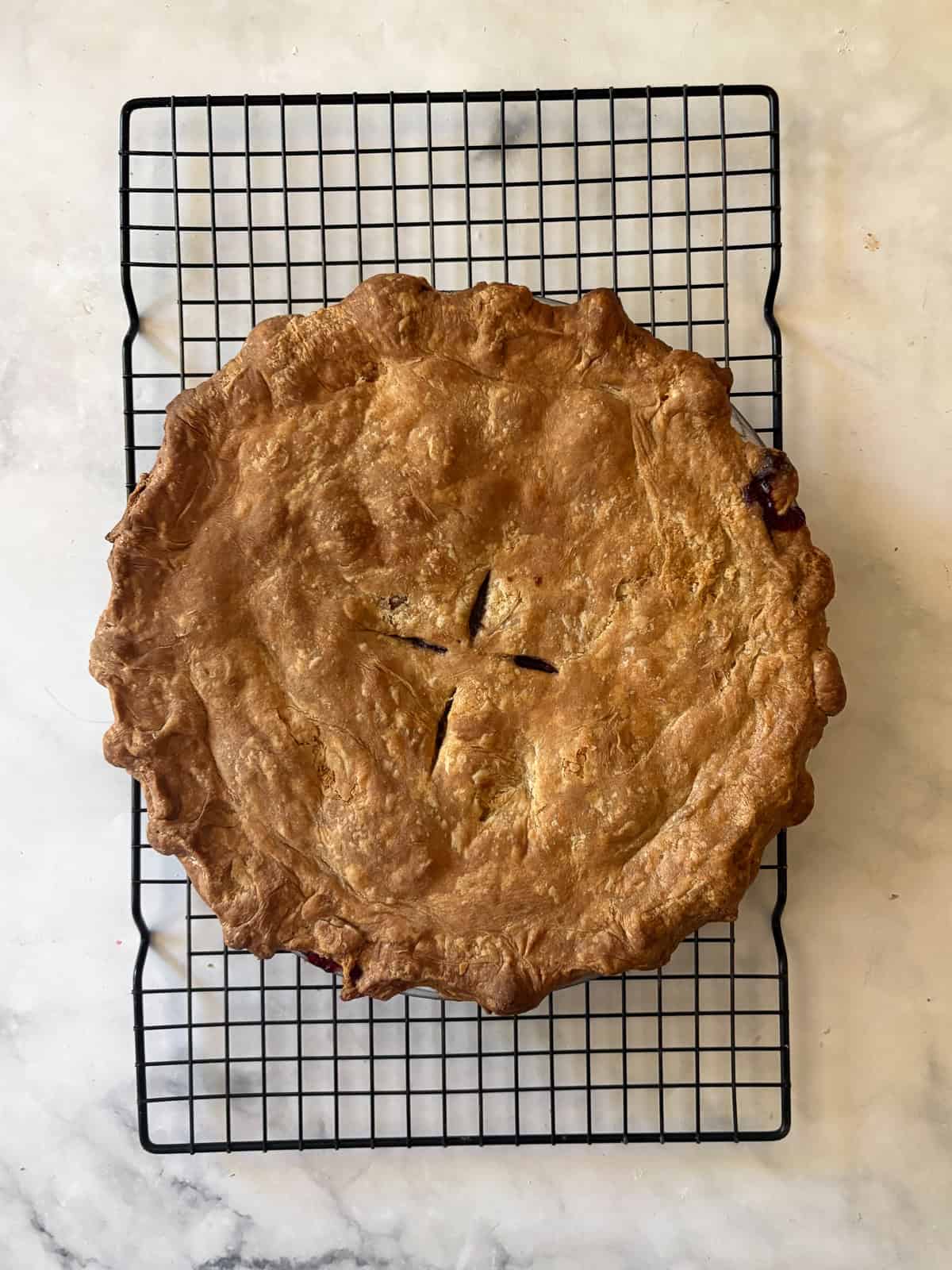 A simple method and ingredients makes this blackberry pie an easy, delicious summer bake. Make gluten-free or not, as needed! A blackberry pie cools on a rack.