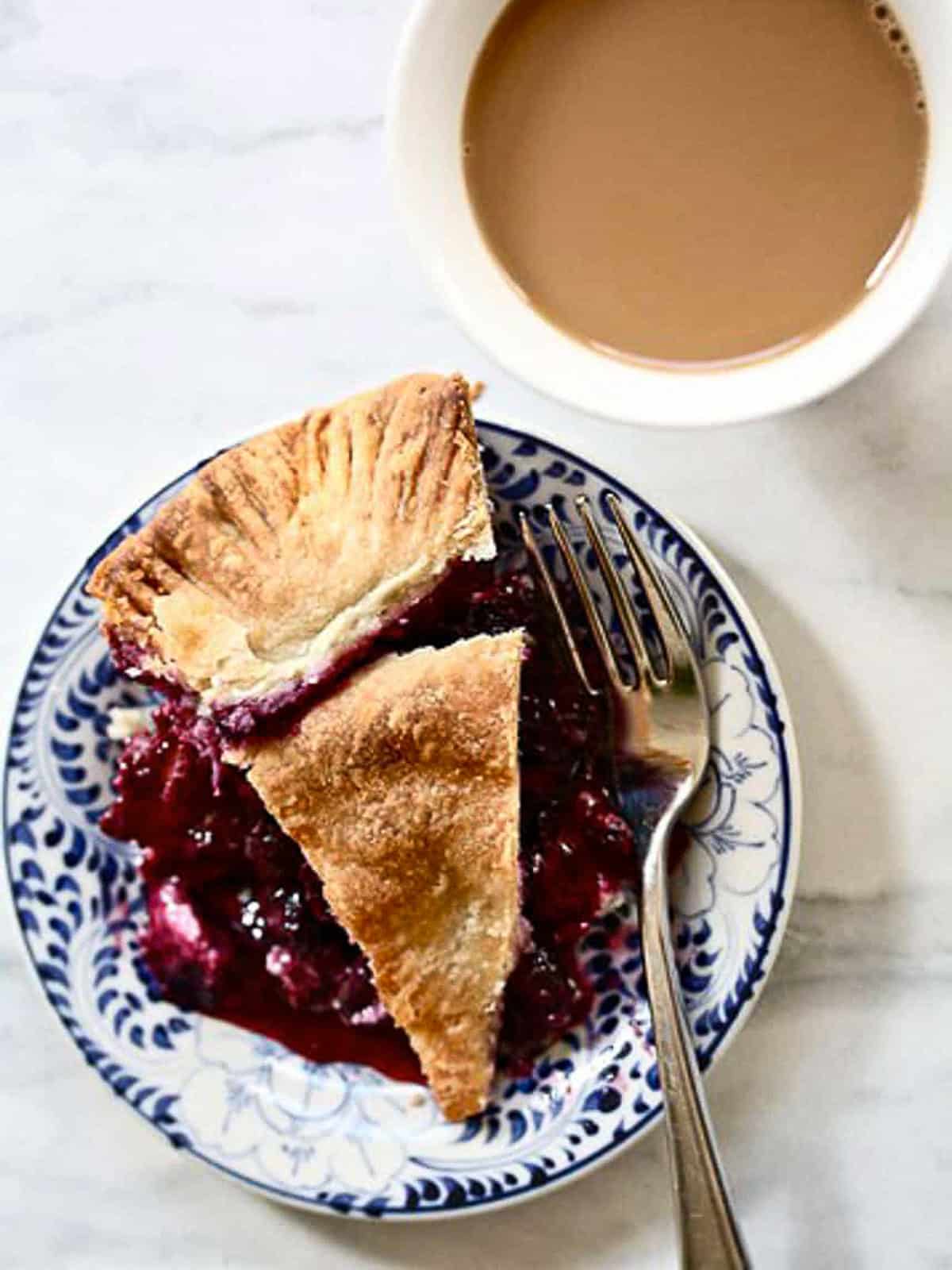 A slice of blueberry blackberry pie on a plate with a fork.
