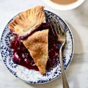 A slice of blueberry blackberry pie on a plate with a fork.