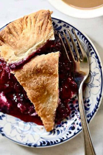 A slice of blueberry blackberry pie on a plate with a fork.