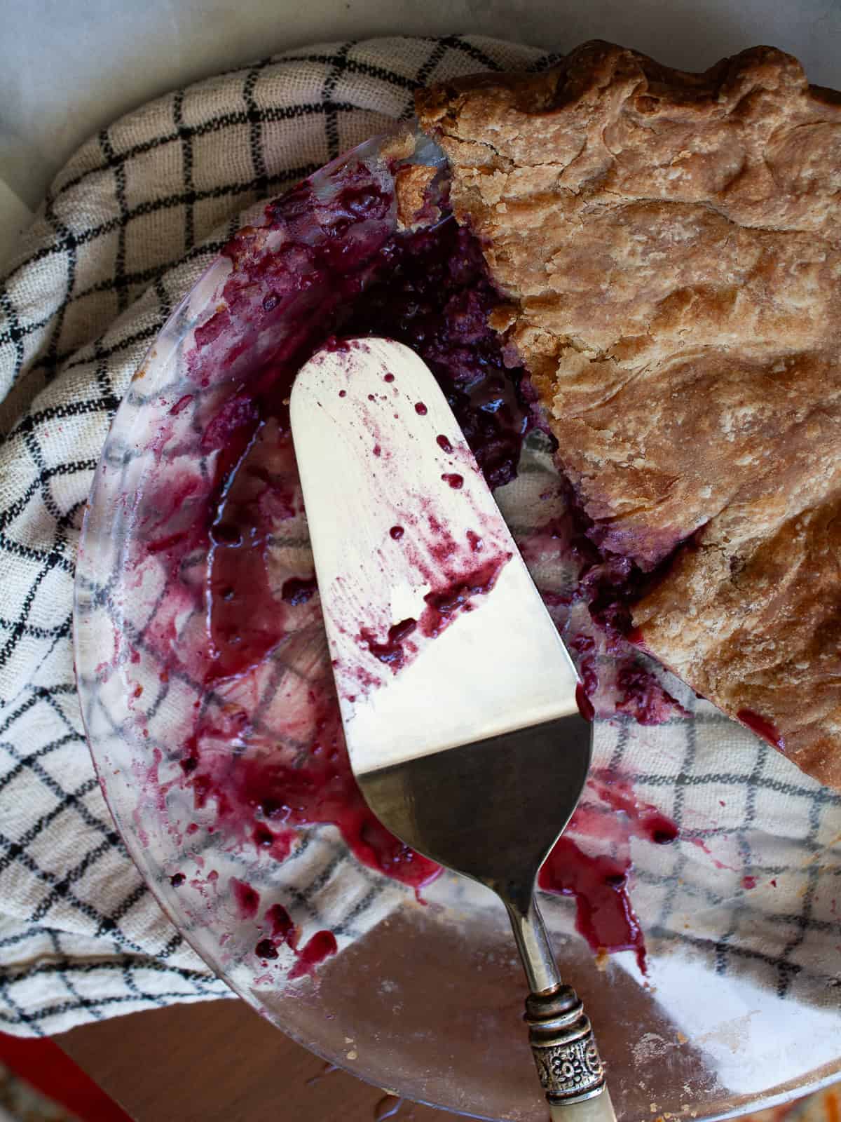 A classic method is used to make this blueberry blackberry pie, which features fresh summer berries folded into a tender crust. A pie server rests in a pie pan with a blueberry blackberry pie.