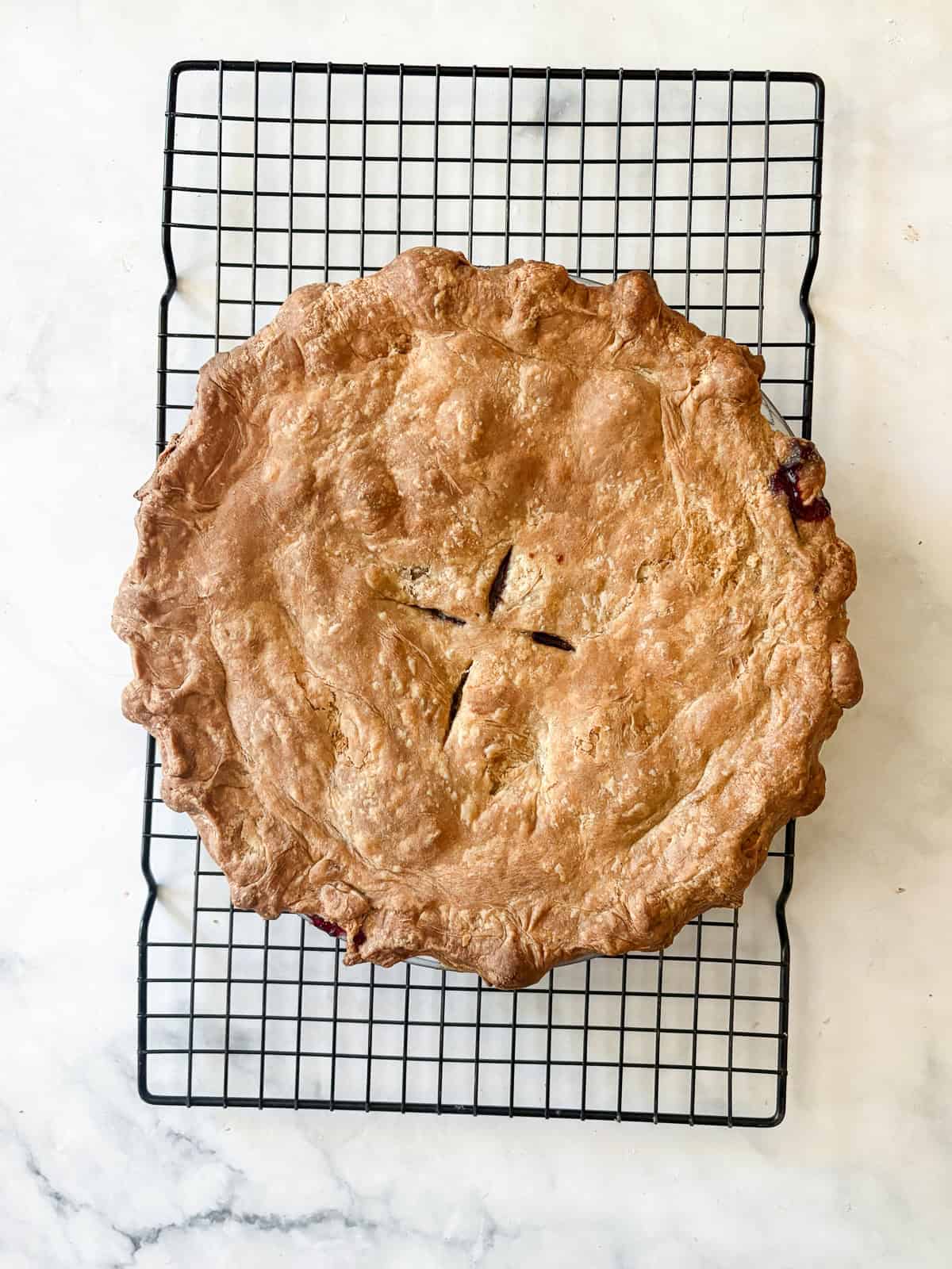 A classic method is used to make this blueberry blackberry pie, which features fresh summer berries folded into a tender crust. A blueberry blackberry pie cools on a rack.