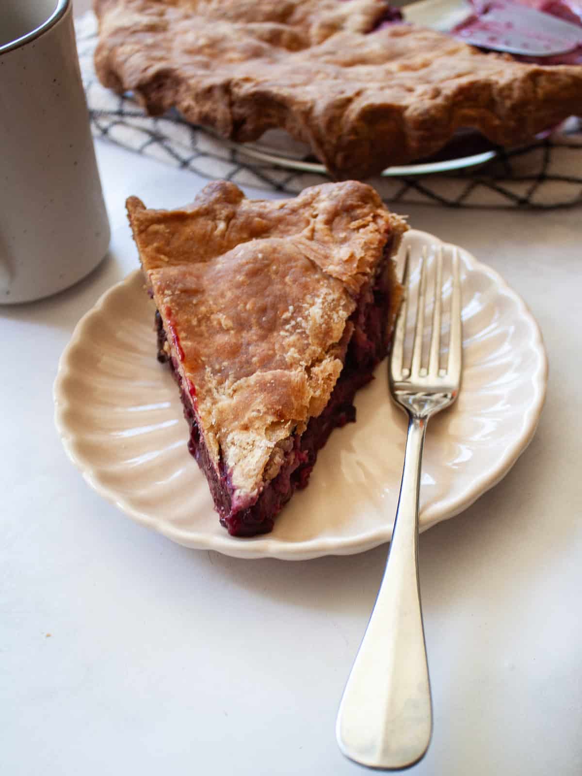A classic method is used to make this blueberry blackberry pie, which features fresh summer berries folded into a tender crust. A slice of blueberry blackberry pie with the pie behind it.