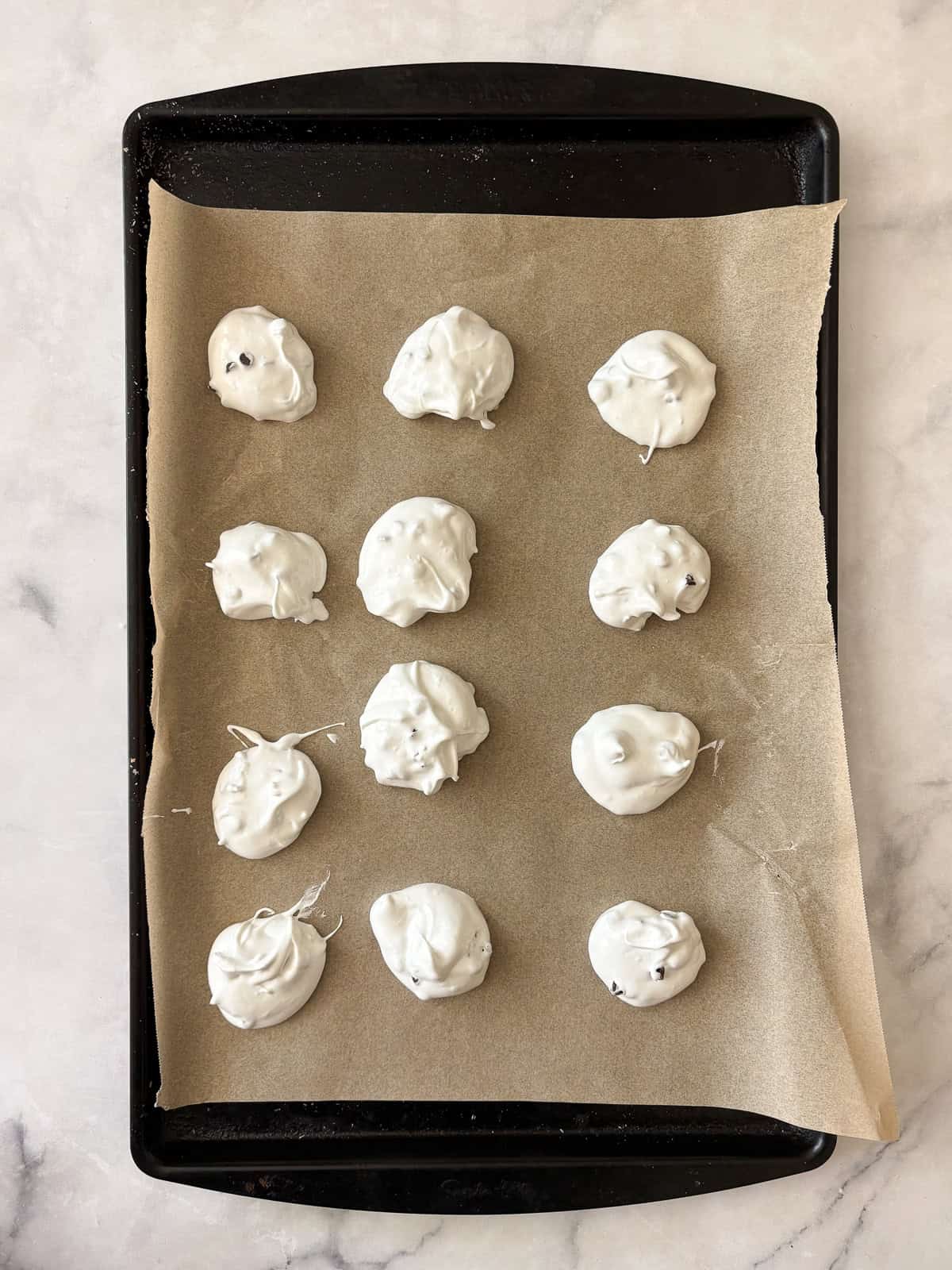 Marshmallowy chocolate chip meringue cookies are studded with mini chocolate chips for bursts of semisweet chocolate in every bite. A tray of unbaked chocolate chip meringue cookies.