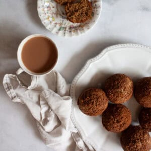 A cup of tea next to cinnamon banana muffins on a plate.