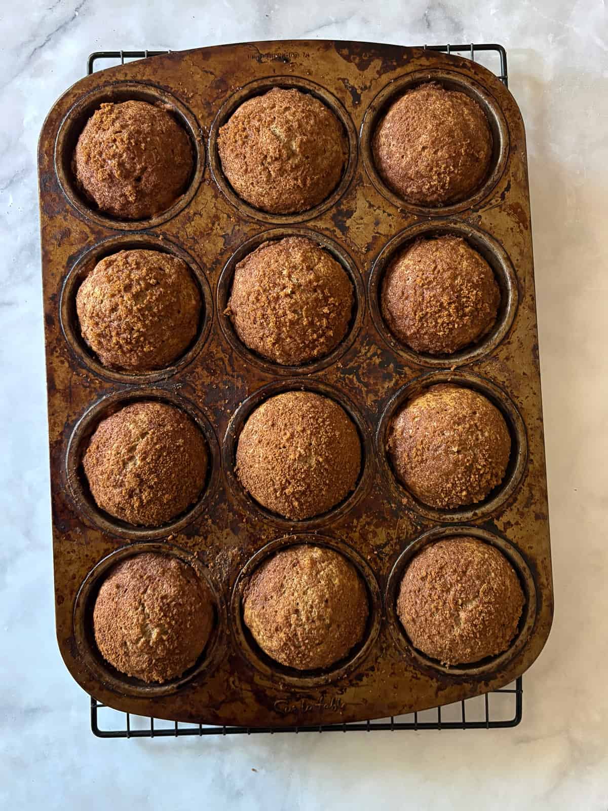 Simple and lightly sweet cinnamon banana muffins are made with wholesome ingredients and finished with a cap of cinnamon and brown sugar. A muffin tin with baked cinnamon banana muffins.