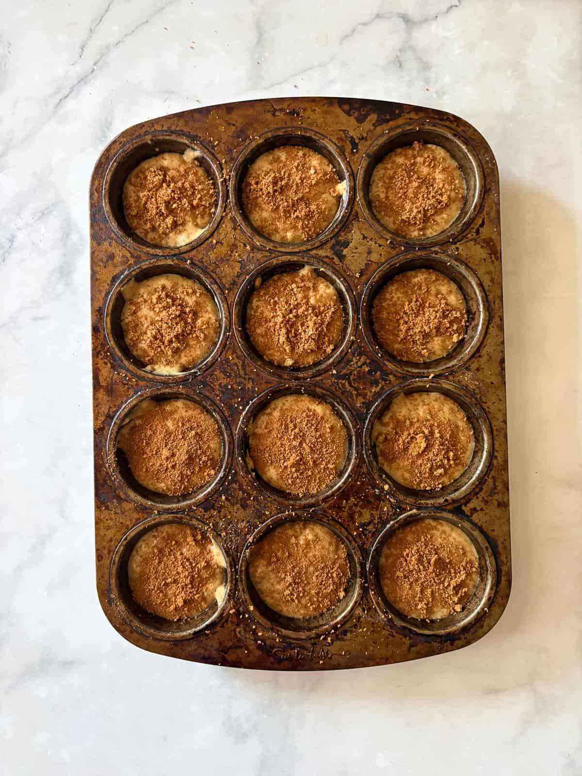 Simple and lightly sweet cinnamon banana muffins are made with wholesome ingredients and finished with a cap of cinnamon and brown sugar. Cinnamon banana muffins in a muffin tin topped with cinnamon sugar before being baked.