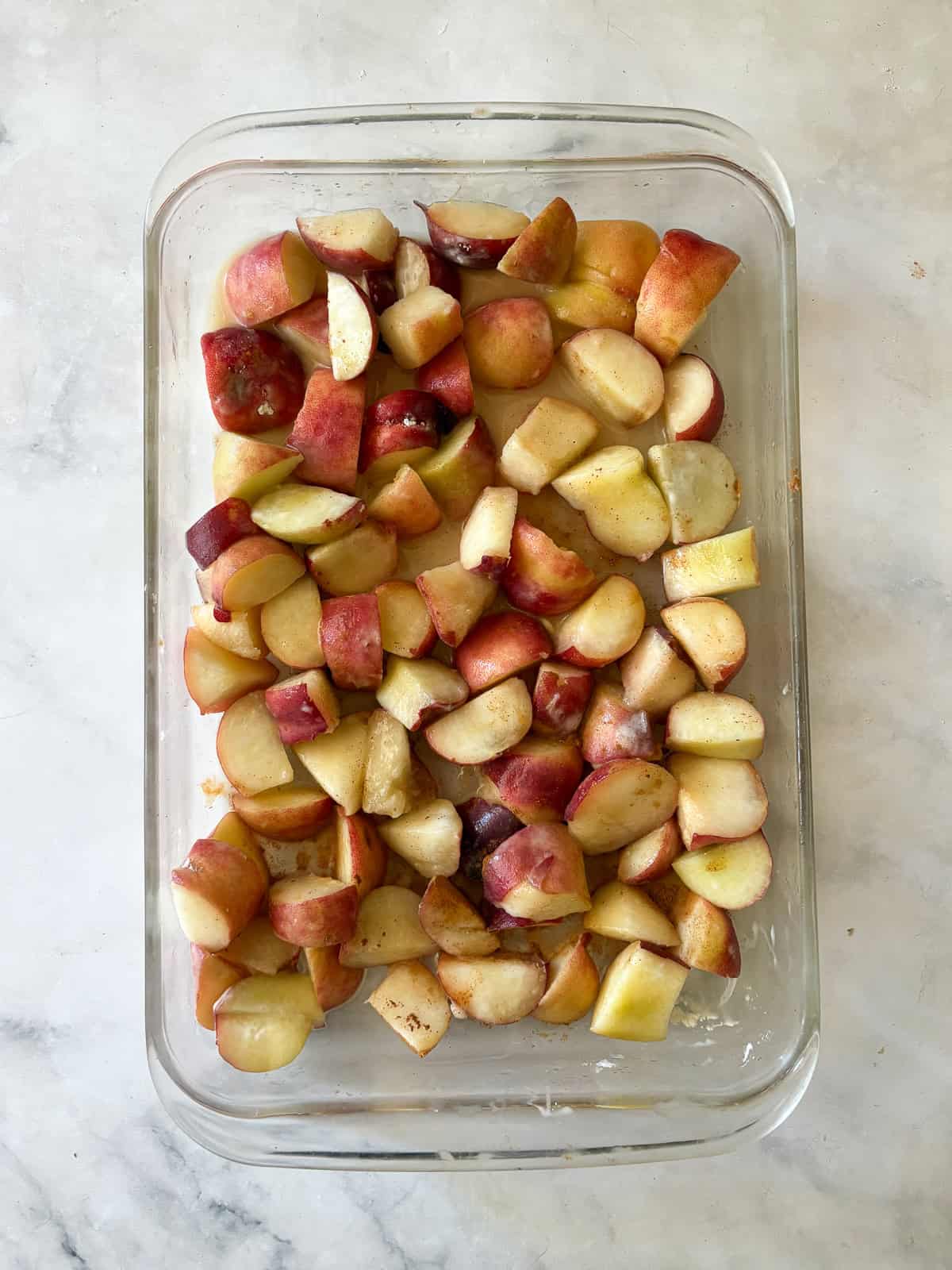 This gluten free peach cobbler features juicy peaches tucked into a pillowy gluten-free batter to make a rustic, simple dessert. Slices peaches in a pan for gluten free peach cobbler.