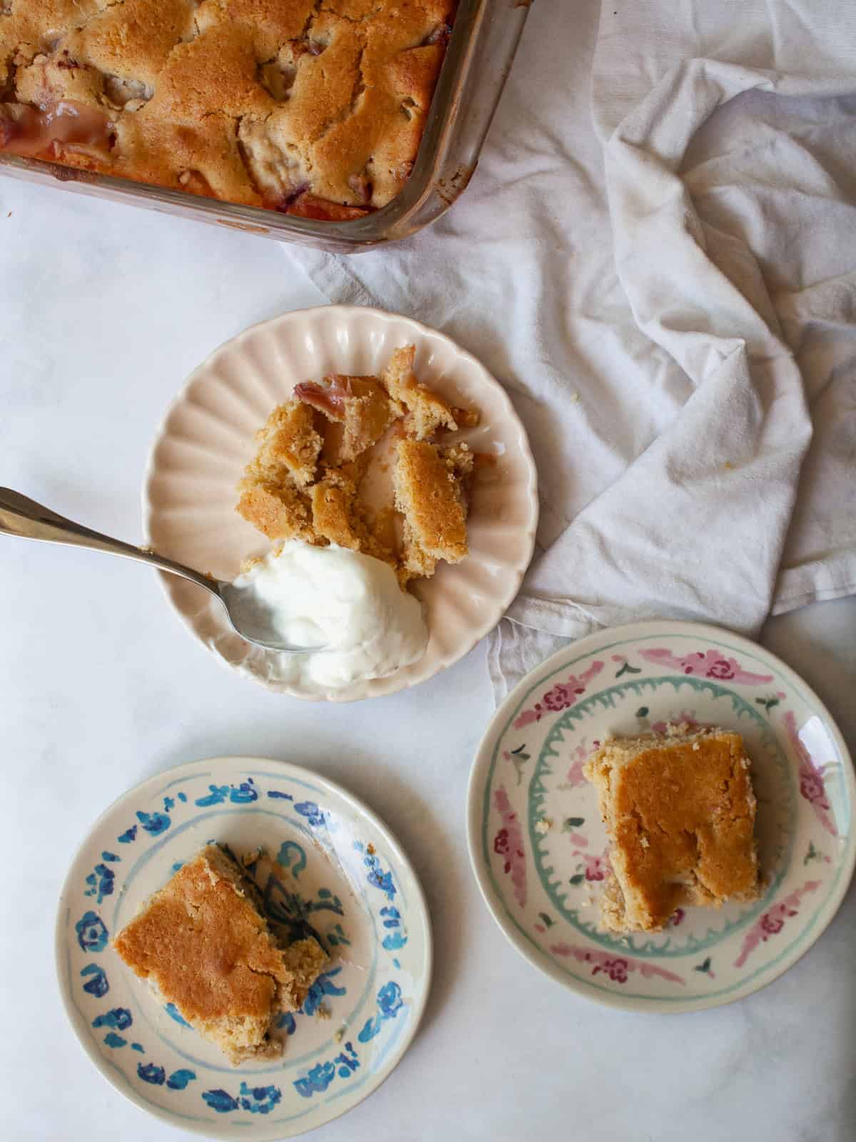Portions of gluten free peach cobbler on plates, one with yogurt.