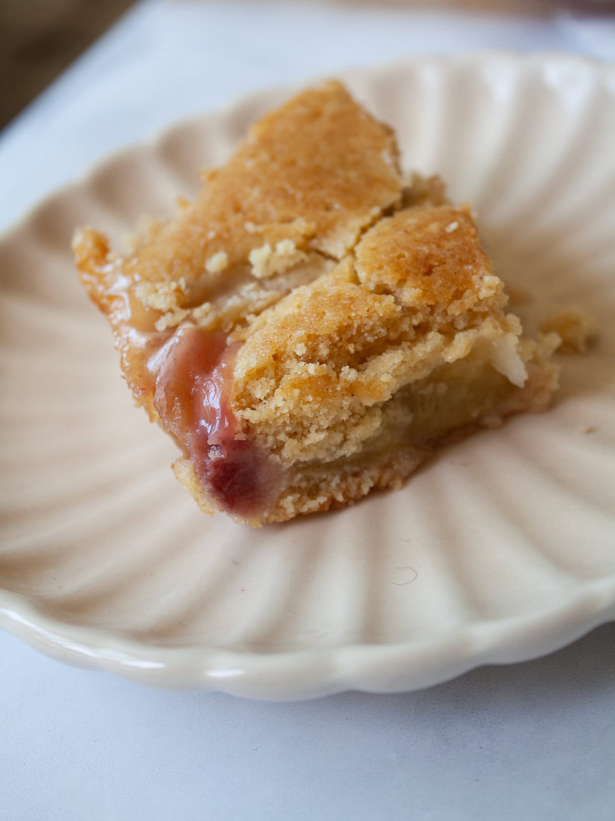 This gluten free peach cobbler features juicy peaches tucked into a pillowy gluten-free batter to make a rustic, simple dessert. A slice of gluten free peach cobbler on a plate.