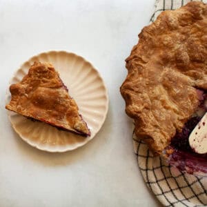 A piece of piece with a whole wheat crust on a plate next to a pie.