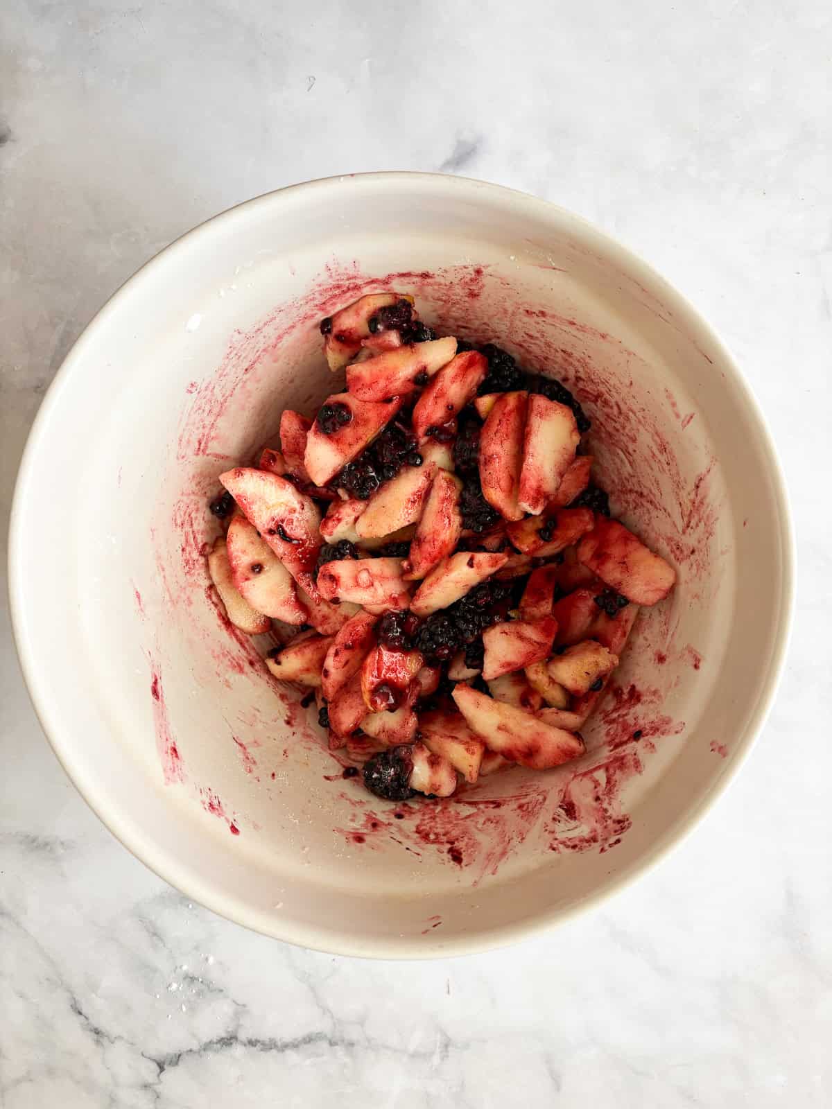 Juicy apples combine with sun-warmed blackberries in this apple blackberry pie. Choose a homemade, gluten-free, or store-bought pie crust. Filling for apple blackberry pie in a bowl.