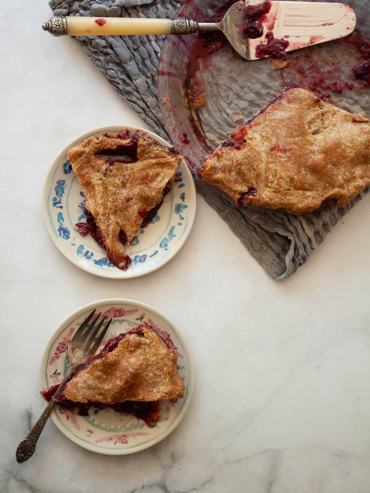 An apple blackberry pie with cut slices of pie next to it.