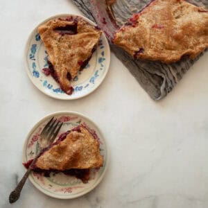 An apple blackberry pie with cut slices of pie next to it.