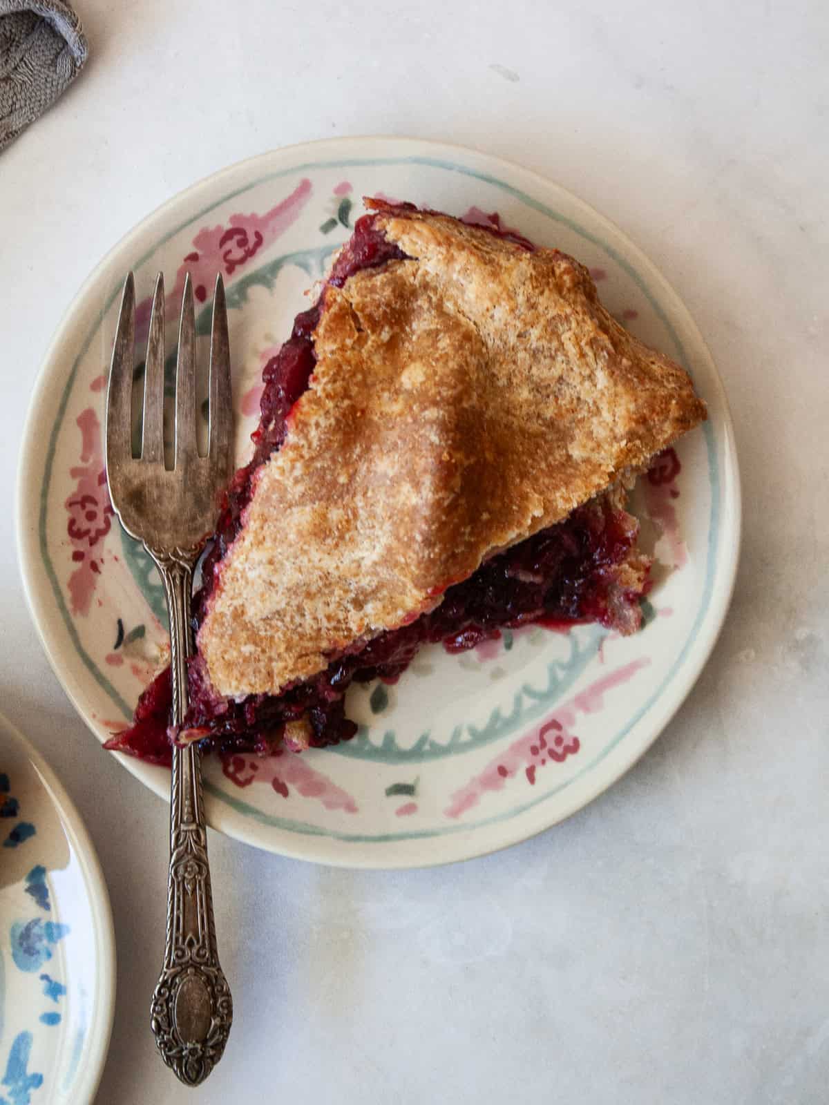 Juicy apples combine with sun-warmed blackberries in this apple blackberry pie. Choose a homemade, gluten-free, or store-bought pie crust. A slice of apple blackberry pie on a plate with a fork.