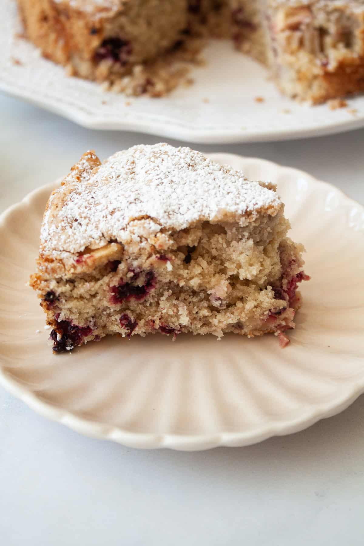 A thick slice of blackberry apple cake on plate.