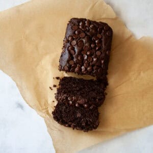 A sliced loaf of double chocolate banana bread on a piece of parchment paper.