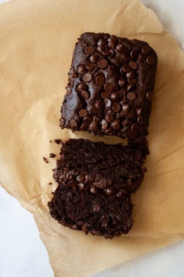 A sliced loaf of double chocolate banana bread on a piece of parchment paper.